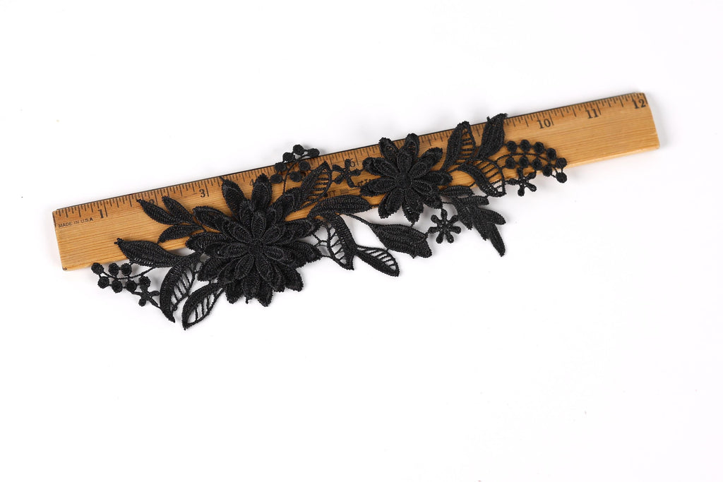a black lace flower attached to a wooden ruler.