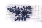 a close-up view of a piece of fabric with a floral design, including blue flowers and leaves. The fabric is placed on a transparent ruler, which is lying on a white surface.