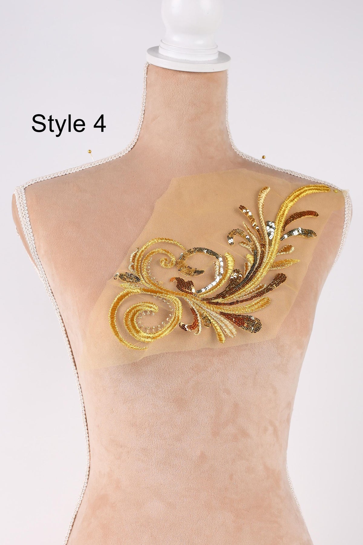 A mannequin with a decorative gold and beige embroidered piece on its bust.