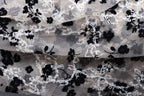 The image is a close-up of a fabric with a floral pattern, featuring black and white flowers and leaves.
