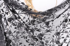 a close-up view of a black lace fabric with a floral pattern. The fabric appears to be made of sheer material, with a delicate and intricate design featuring black lace and floral elements. The fabric is displayed against a plain white background, highlighting its texture and design.