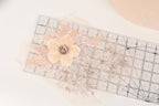 a clear ruler with a delicate flower design on it, placed on a white surface.