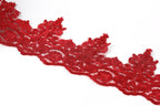 A close-up view of a red, intricately designed lace trim against a white background.