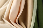 a close-up view of a fabric with a soft, crumpled texture in various shades of peach and green.