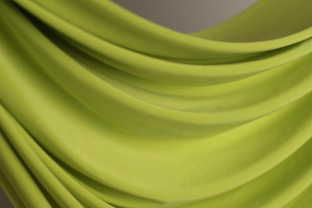 A close-up view of a bright green fabric, possibly a sheer or sheer-like material, with a soft, flowing texture.