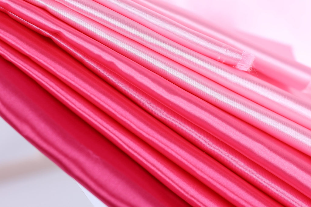 A close-up view of a fabric with a gradient of pink and red colors, creating a visually striking and vibrant appearance.