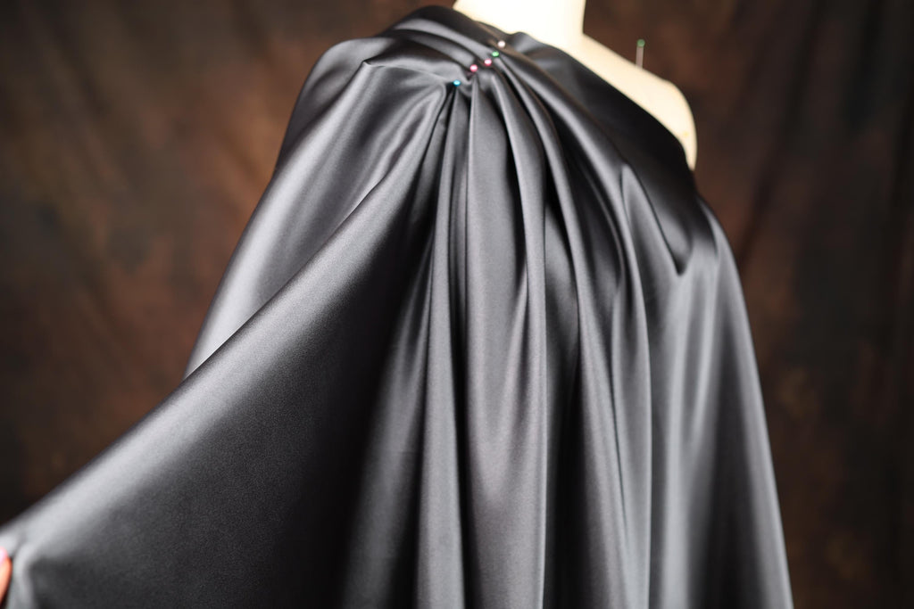 a woman wearing a black cape with a flower on it