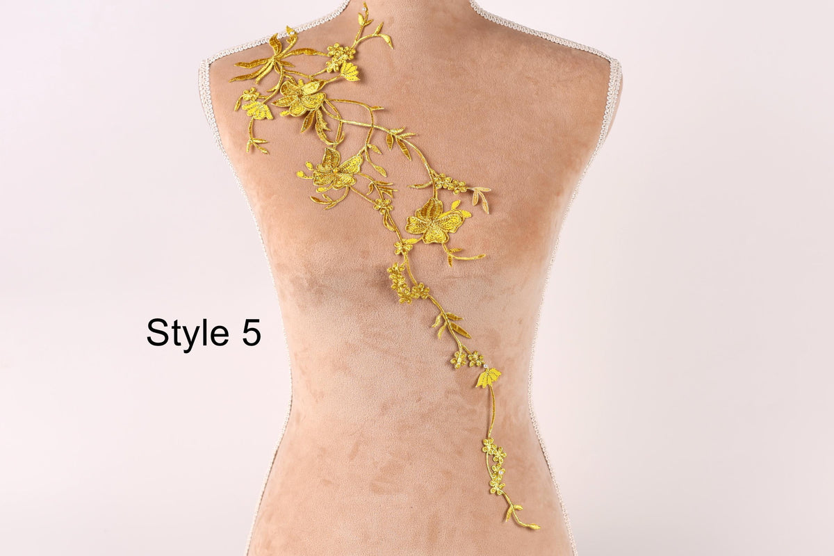 A mannequin with a gold floral design on its back, featuring a long, flowing arrangement of yellow flowers and leaves.