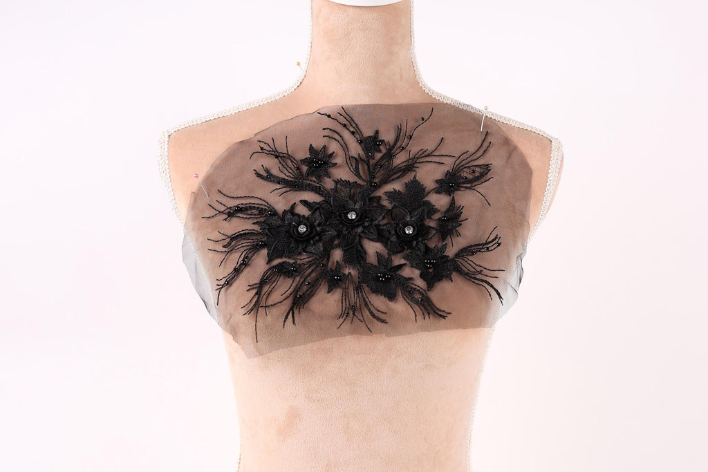 A mannequin with a decorative black lace design on its chest area.