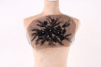 A mannequin with a decorative black lace design on its chest area.