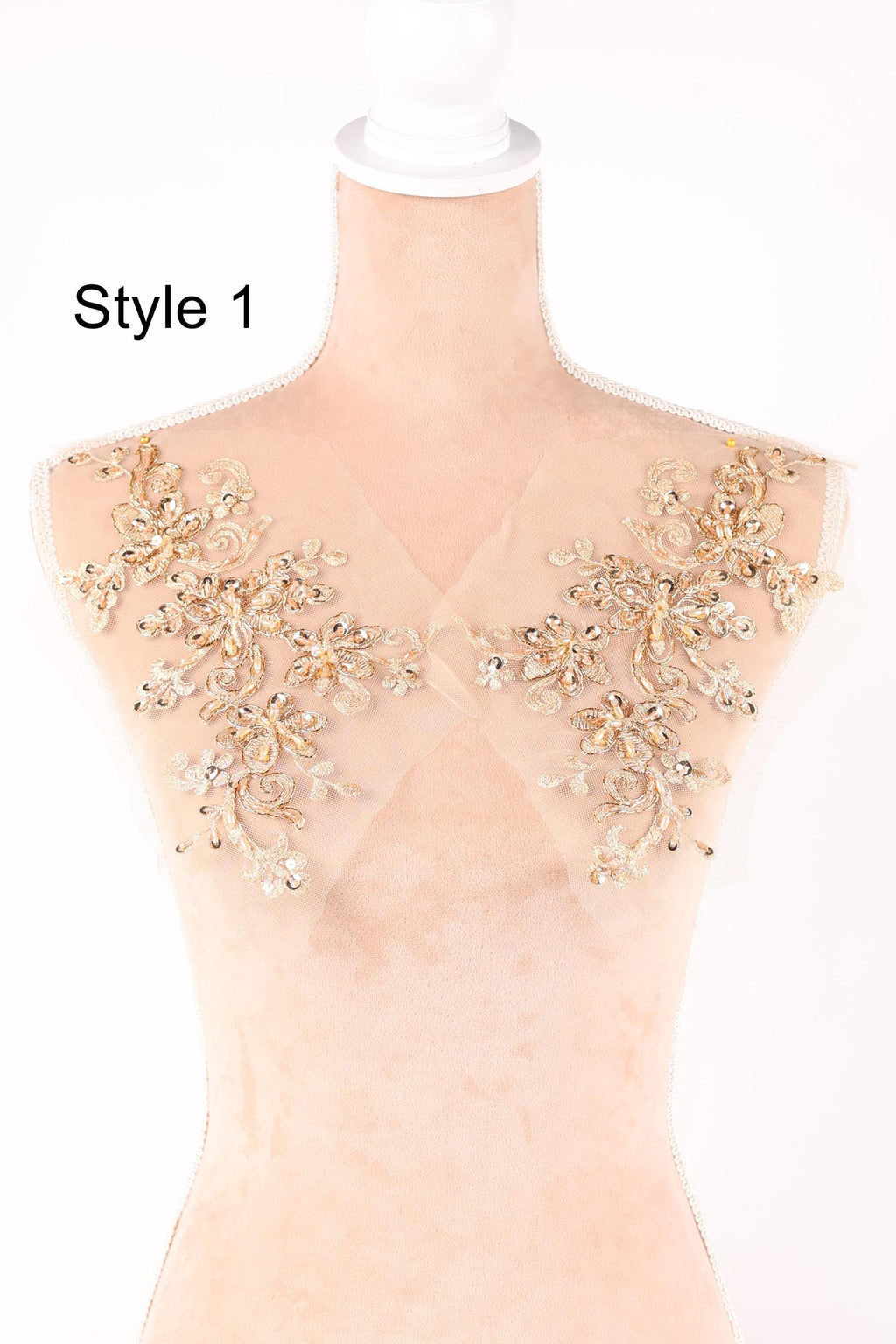 A mannequin with a beige fabric shoulder and gold floral embellishments on the shoulders.