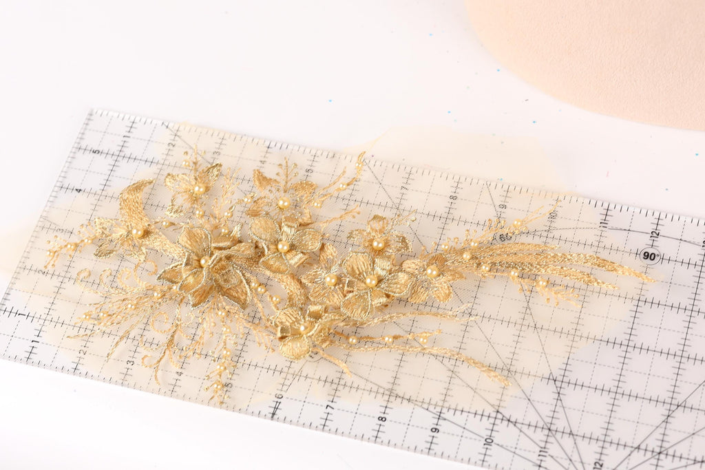 a close-up view of a delicate gold floral arrangement on a transparent ruler.