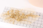 a close-up view of a delicate gold floral arrangement on a transparent ruler.