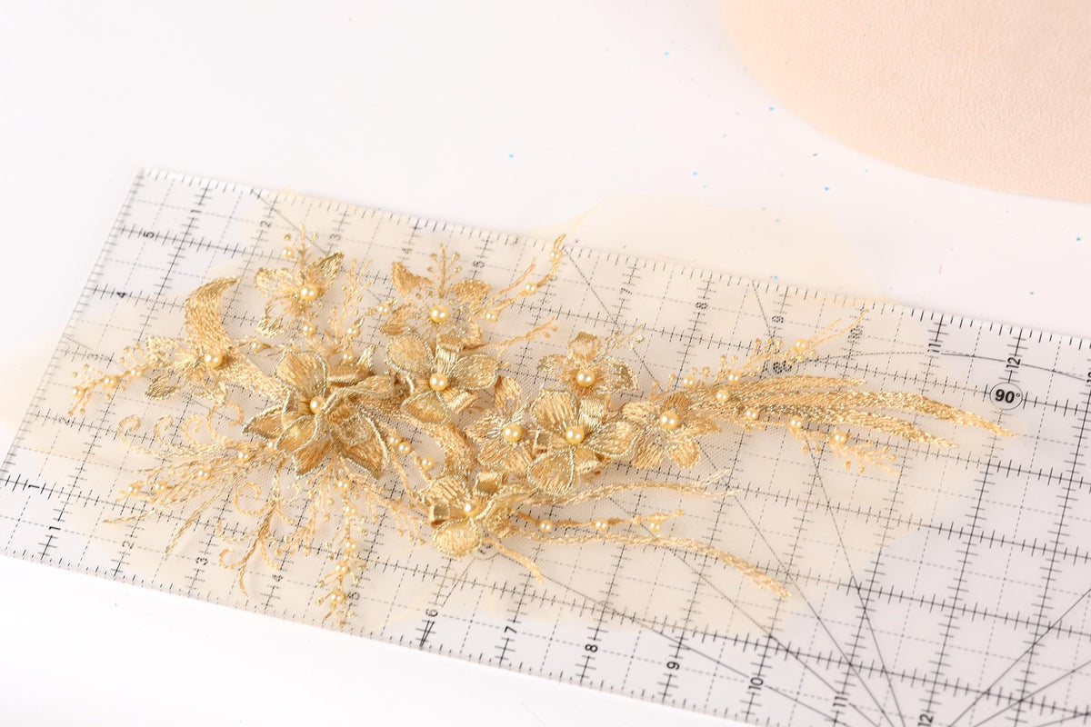 a close-up view of a delicate gold floral arrangement on a transparent ruler.