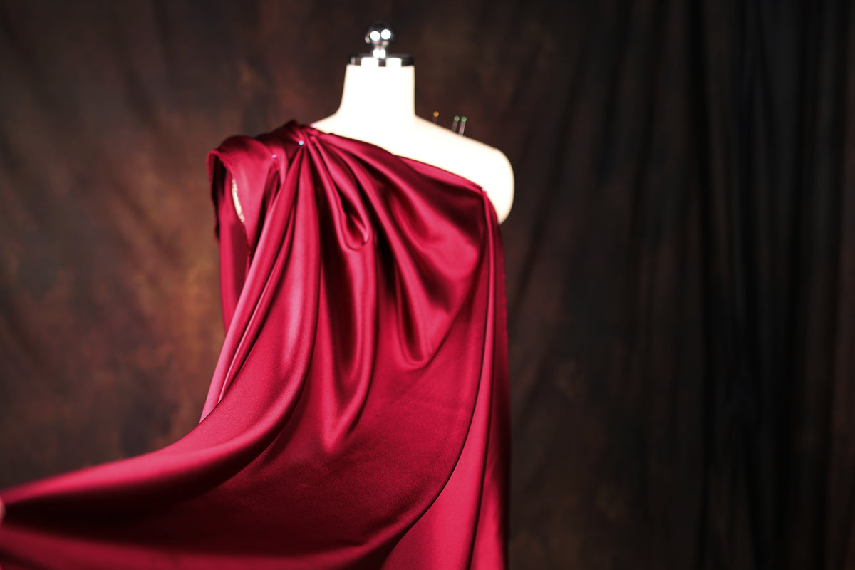 A mannequin wearing a red satin dress with a draped, flowing skirt.