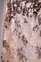 The image is a close-up of a fabric with a textured, multicolored pattern. The fabric appears to be a piece of sheer material, possibly used for curtains or drapes. The pattern consists of various shades of brown, pink, and white, creating a visually striking and intricate design.