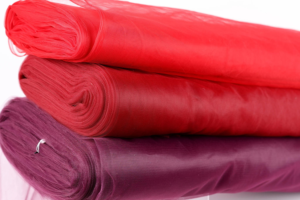 three rolls of fabric stacked on top of each other, with the topmost roll being red and the other two rolls being purple.