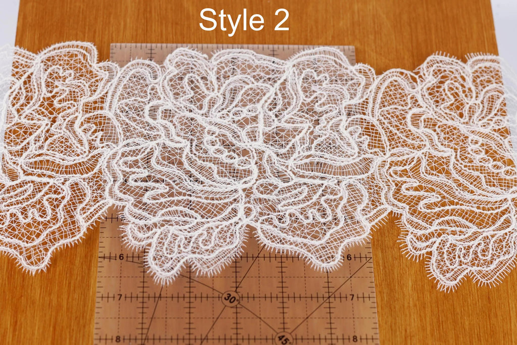 a close-up view of a delicate white lace pattern, with the intricate details of the lace visible. The lace appears to be a part of a larger design, as it is placed on a wooden surface. A ruler is also present in the image, likely used for measuring or marking the lace pattern.