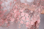 A close-up view of a delicate, pink floral fabric with numerous small pink roses and leaves attached to it.