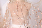 A mannequin wearing a sheer, peach-colored veil with delicate leaf-like patterns.