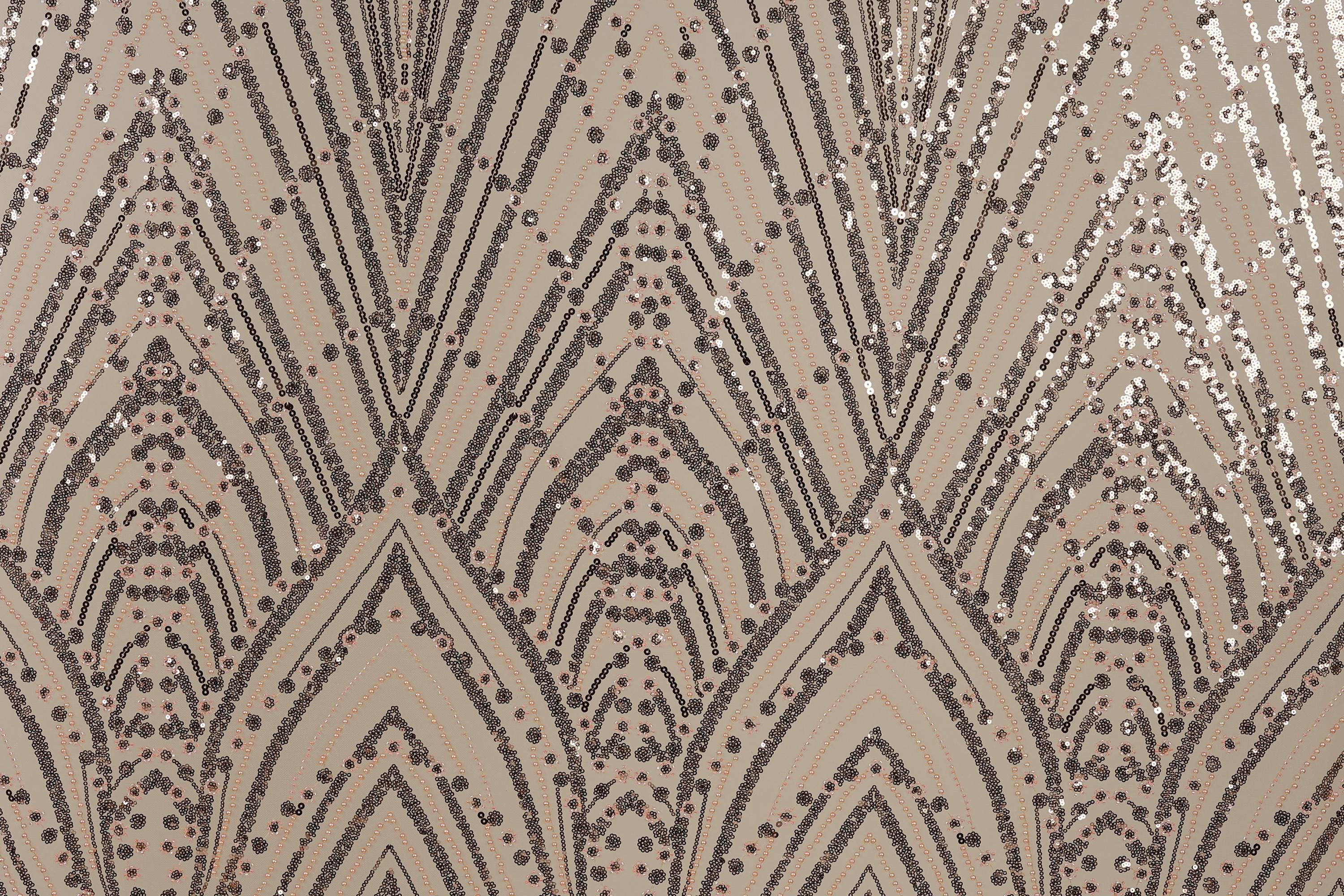 a close-up view of a patterned fabric with a repeating geometric design. The design consists of a series of arched shapes and lines, interspersed with small circular dots. The overall color scheme of the pattern is a mix of brown and beige, with some areas of black and white. The pattern appears to be a decorative textile or fabric, possibly used for clothing or home decor.