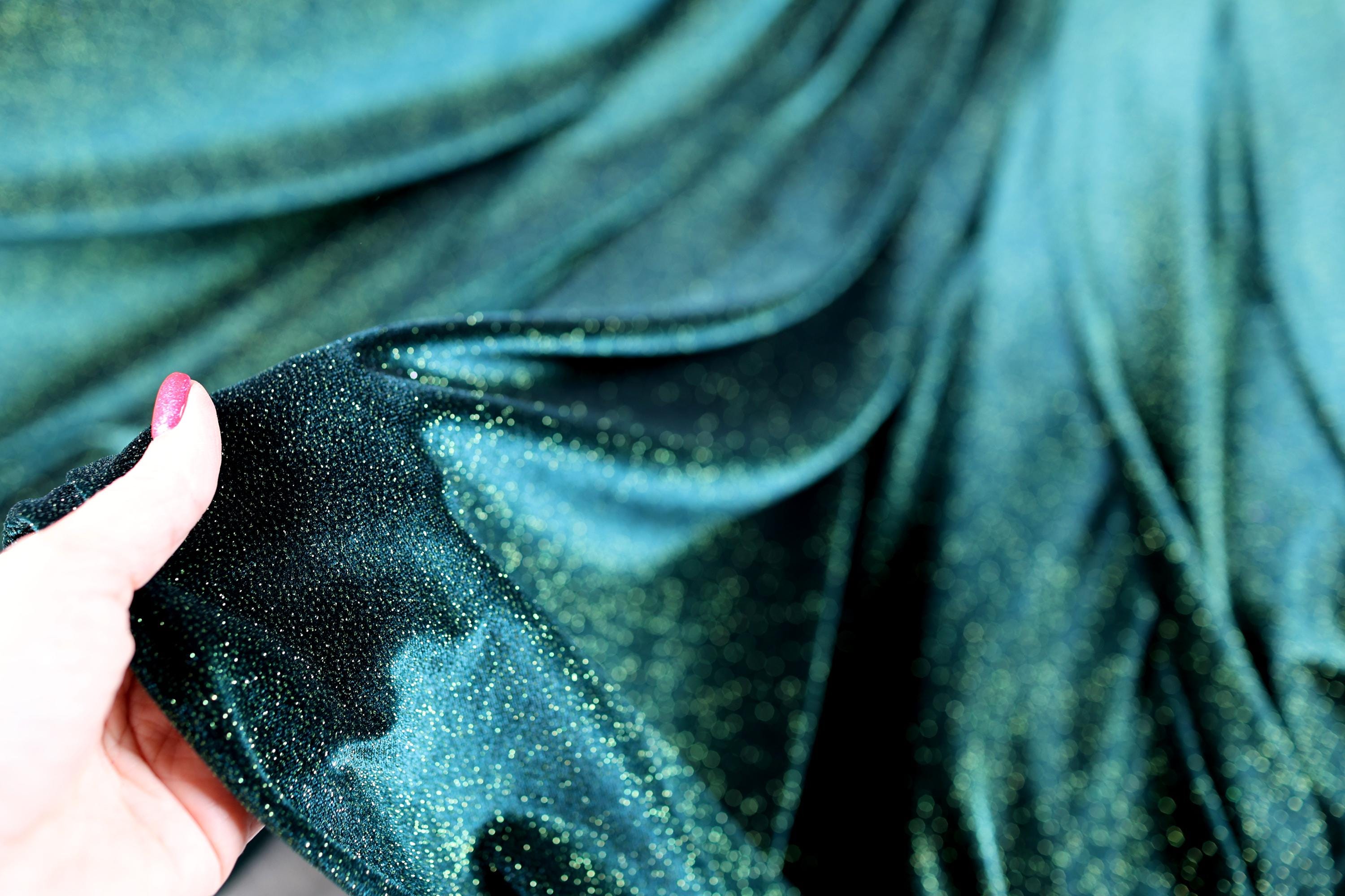 a woman's hand holding a cell phone in front of a curtain