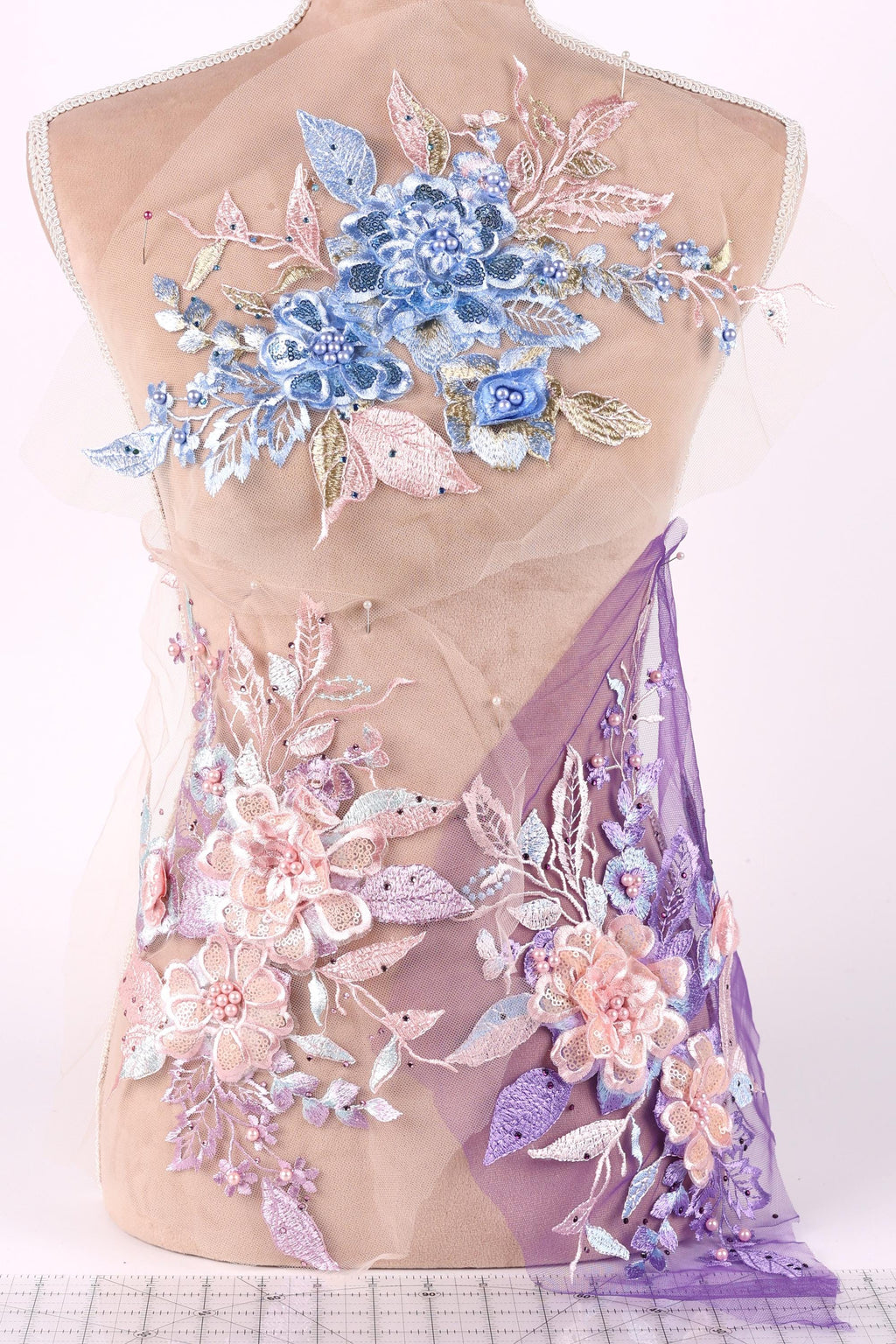 a mannequin with a dress adorned with intricate floral embroidery in shades of blue, pink, and purple.