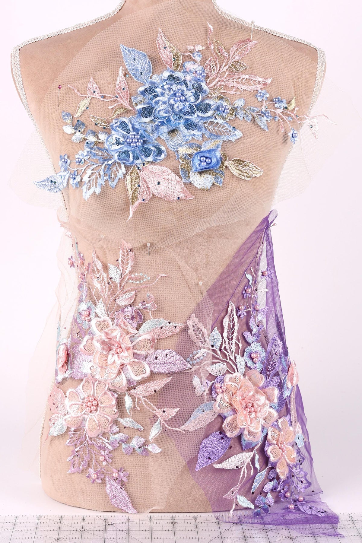 a mannequin with a dress adorned with intricate floral embroidery in shades of blue, pink, and purple.