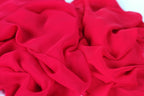 The image is a close-up of a red fabric, possibly silk or chiffon, with a crumpled and wrinkled texture.