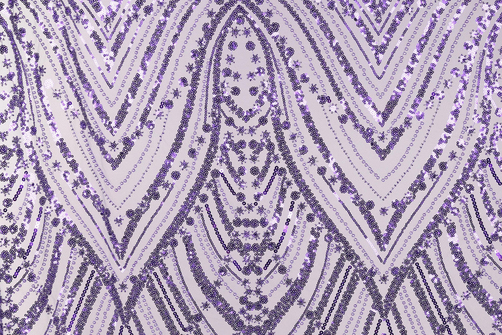 a close-up view of a fabric with a repeating pattern of purple and white sequins. The pattern consists of diagonal lines and curves, creating a visually striking and intricate design. The fabric appears to be made of a material that has a shiny, sequined texture, adding a touch of sparkle and elegance to the overall appearance.