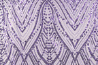 a close-up view of a fabric with a repeating pattern of purple and white sequins. The pattern consists of diagonal lines and curves, creating a visually striking and intricate design. The fabric appears to be made of a material that has a shiny, sequined texture, adding a touch of sparkle and elegance to the overall appearance.