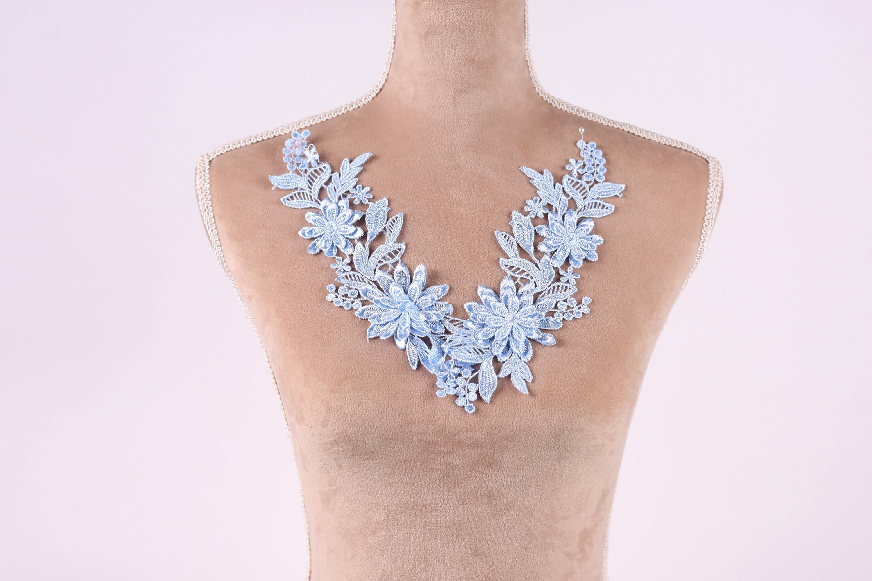 A mannequin wearing a necklace with blue floral embroidery.