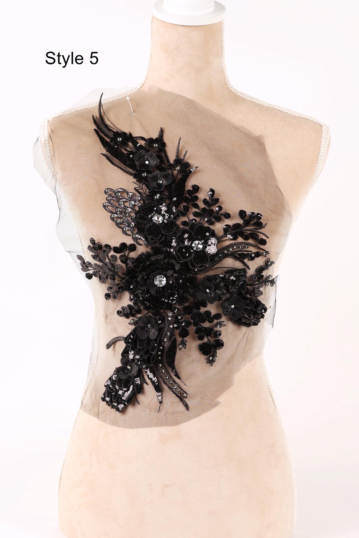 A mannequin wearing a dress with a black floral embellishment on the chest area.