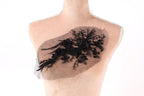 A mannequin torso with a decorative black lace piece on it.