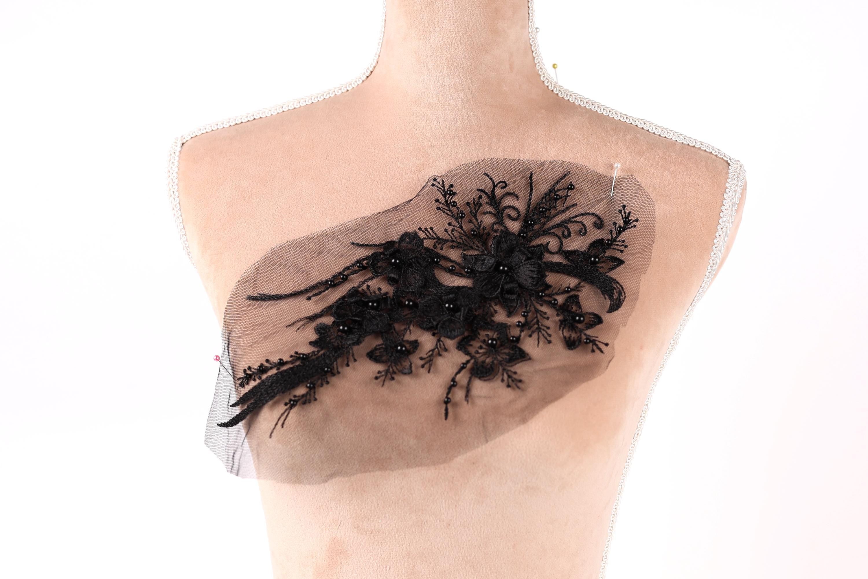 A mannequin torso with a decorative black lace piece on it.