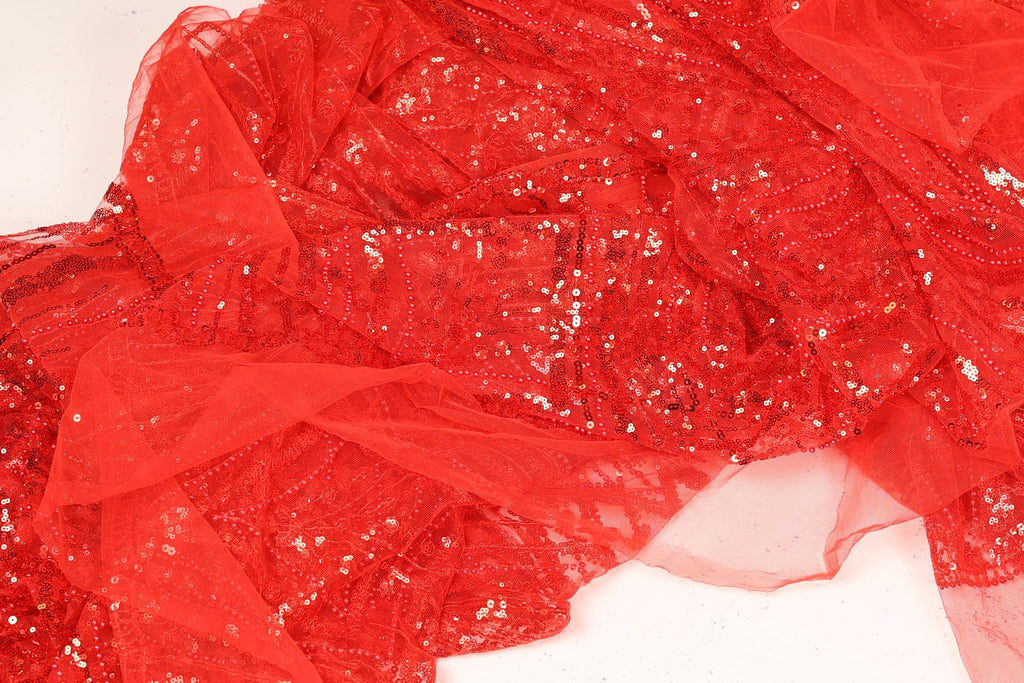 The image is a close-up of a red sequined fabric, with a textured and shiny appearance.