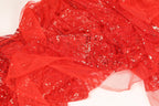 The image is a close-up of a red sequined fabric, with a textured and shiny appearance.
