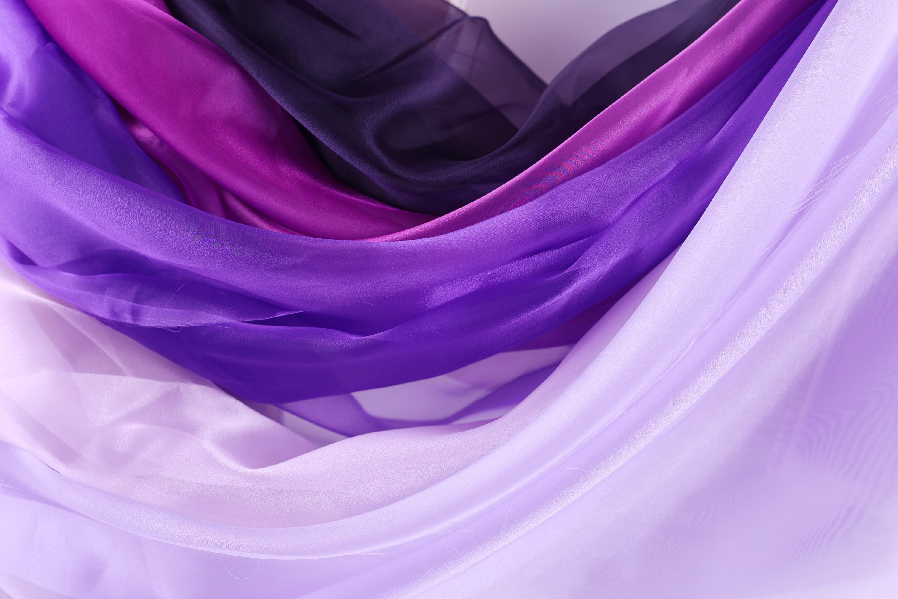 a close-up view of a variety of colorful fabric swatches, including shades of purple, pink, and white.