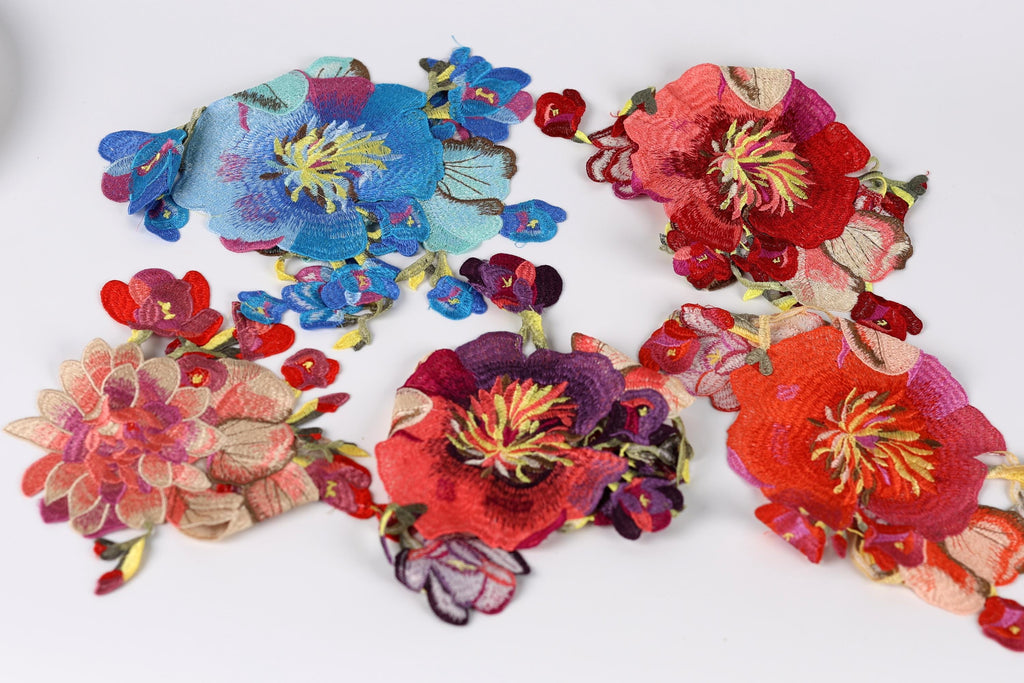 a variety of colorful, intricately embroidered flowers in different shapes and sizes, arranged on a white background.