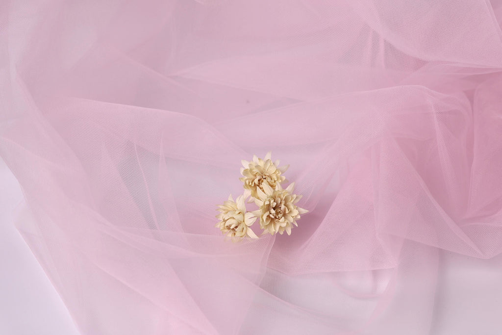 a delicate arrangement of three small white flowers against a soft pink background.
