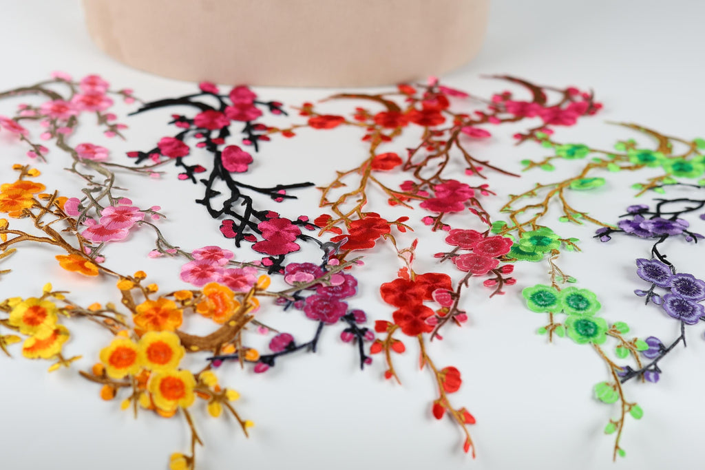 a variety of colorful floral embroidery pieces, including pink, red, green, and purple flowers, arranged on a white surface.