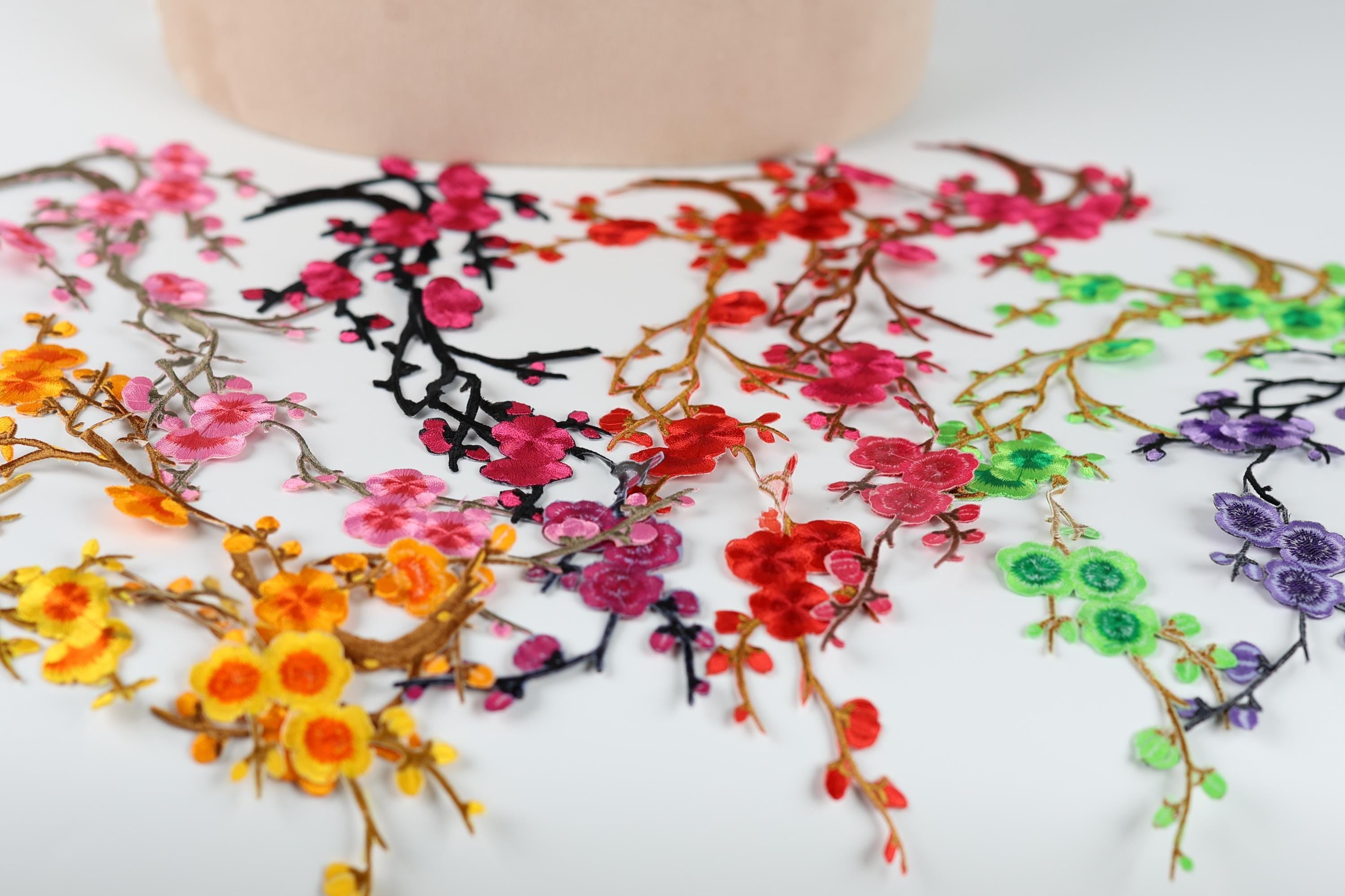 a variety of colorful floral embroidery pieces, including pink, red, green, and purple flowers, arranged on a white surface.