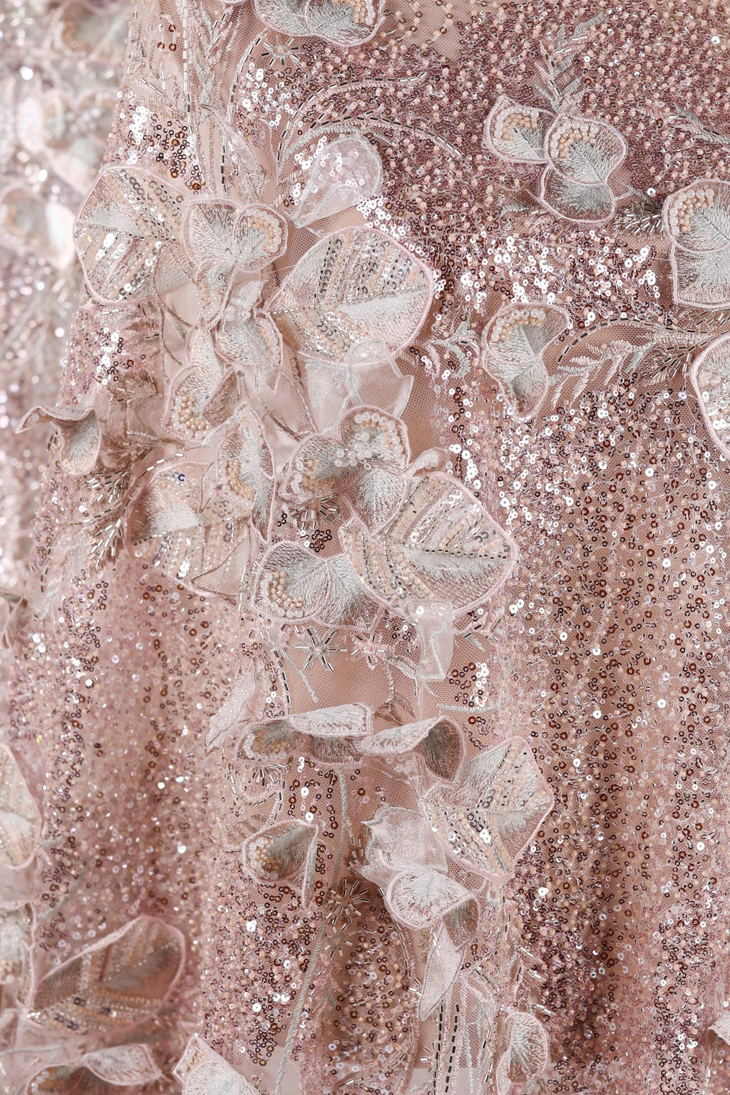 The image is a close-up of a delicate, pink sequined dress with intricate floral embroidery.