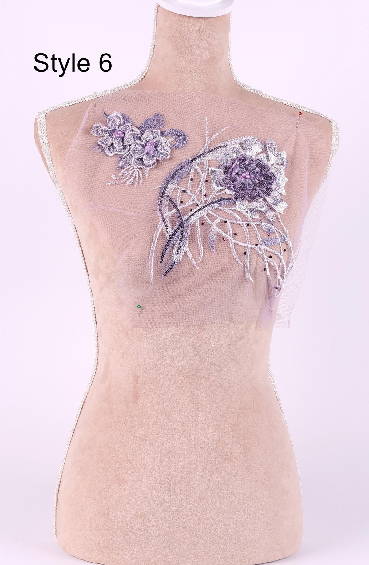 A mannequin with a pink fabric bust and a clear fabric patch with purple flowers and white flowers attached to it.