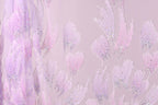 a close-up view of a fabric with a delicate, pastel-colored floral pattern. The fabric appears to be made of a sheer material, with a pink and purple color scheme. The pattern consists of numerous small, intricately designed flowers or leaves, each adorned with tiny glitter or sequin accents. The overall appearance of the fabric is soft and delicate, with a subtle, elegant aesthetic.