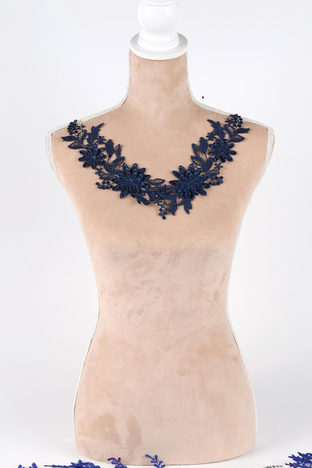 A mannequin wearing a necklace with blue floral embroidery.
