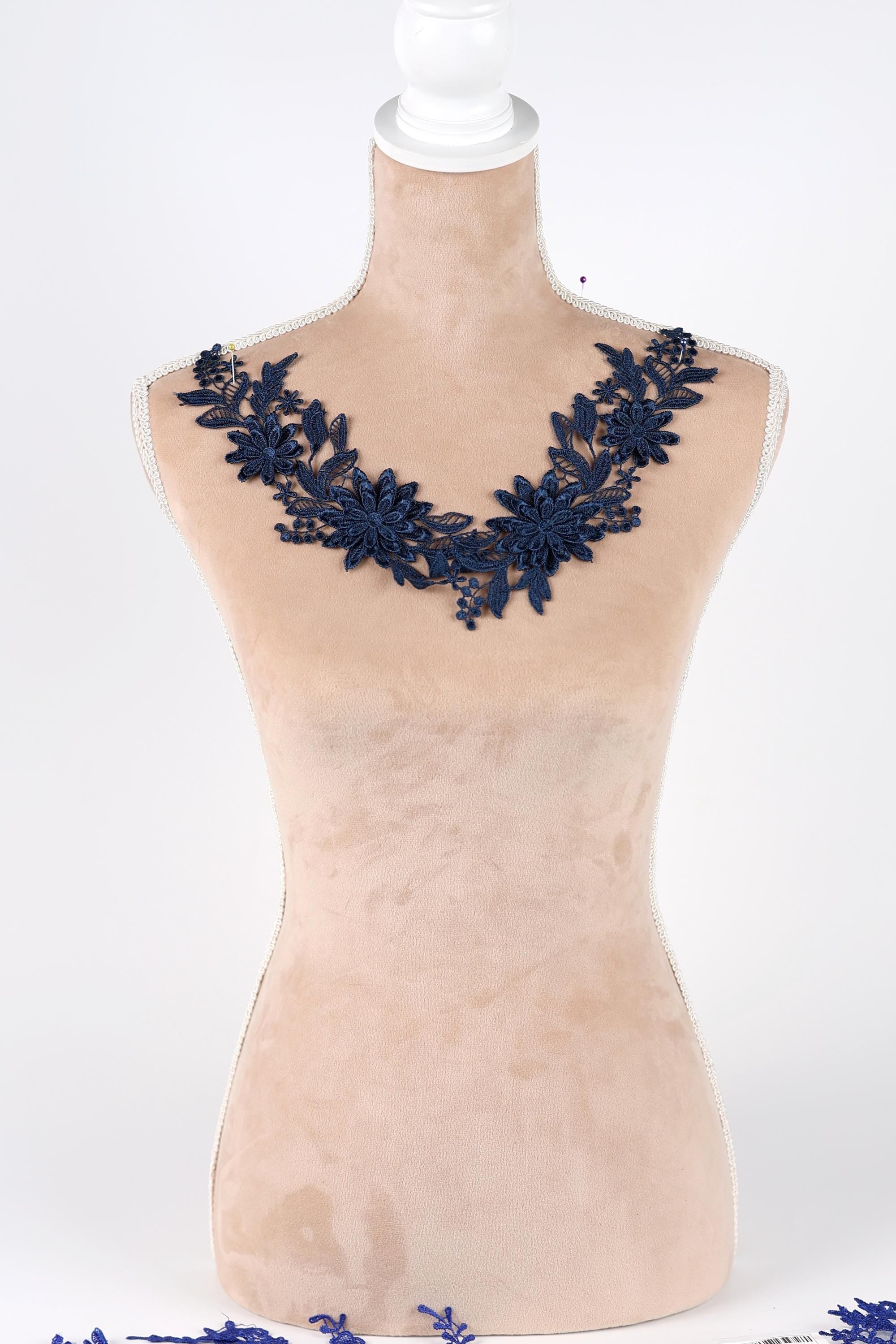A mannequin wearing a necklace with blue floral embroidery.