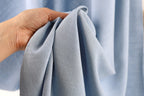 A hand is holding a folded light blue fabric, which appears to be a piece of clothing or textile.