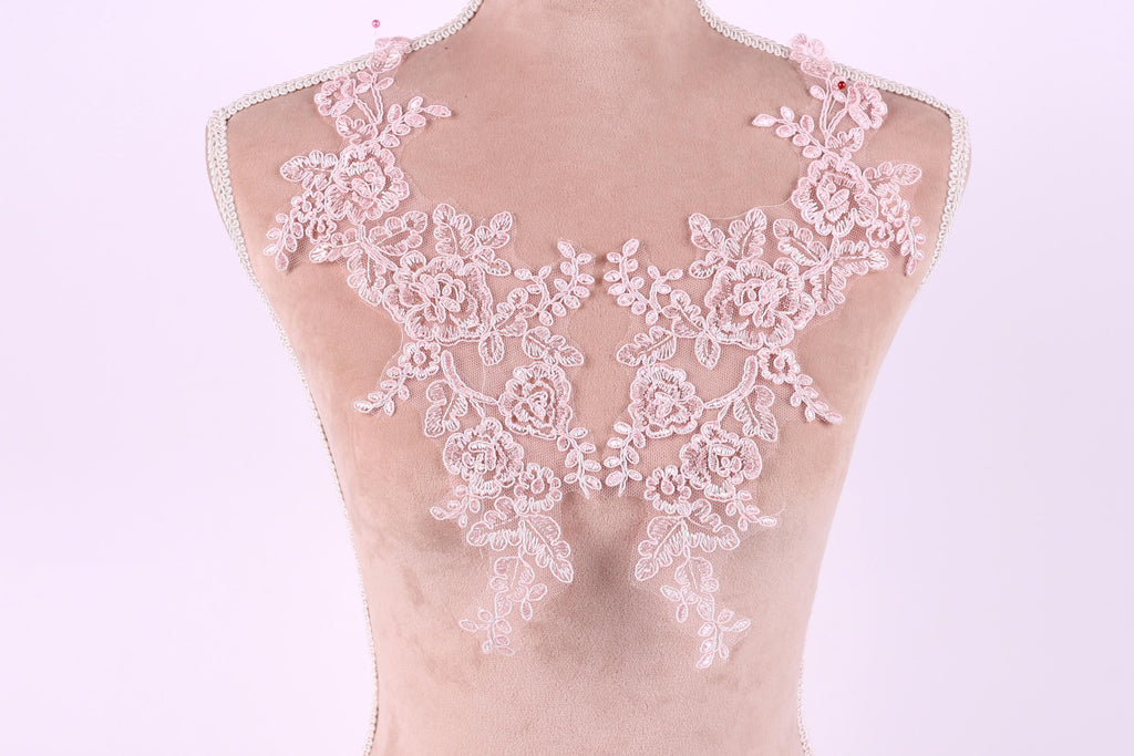 A mannequin wearing a pink lace dress with intricate floral patterns.