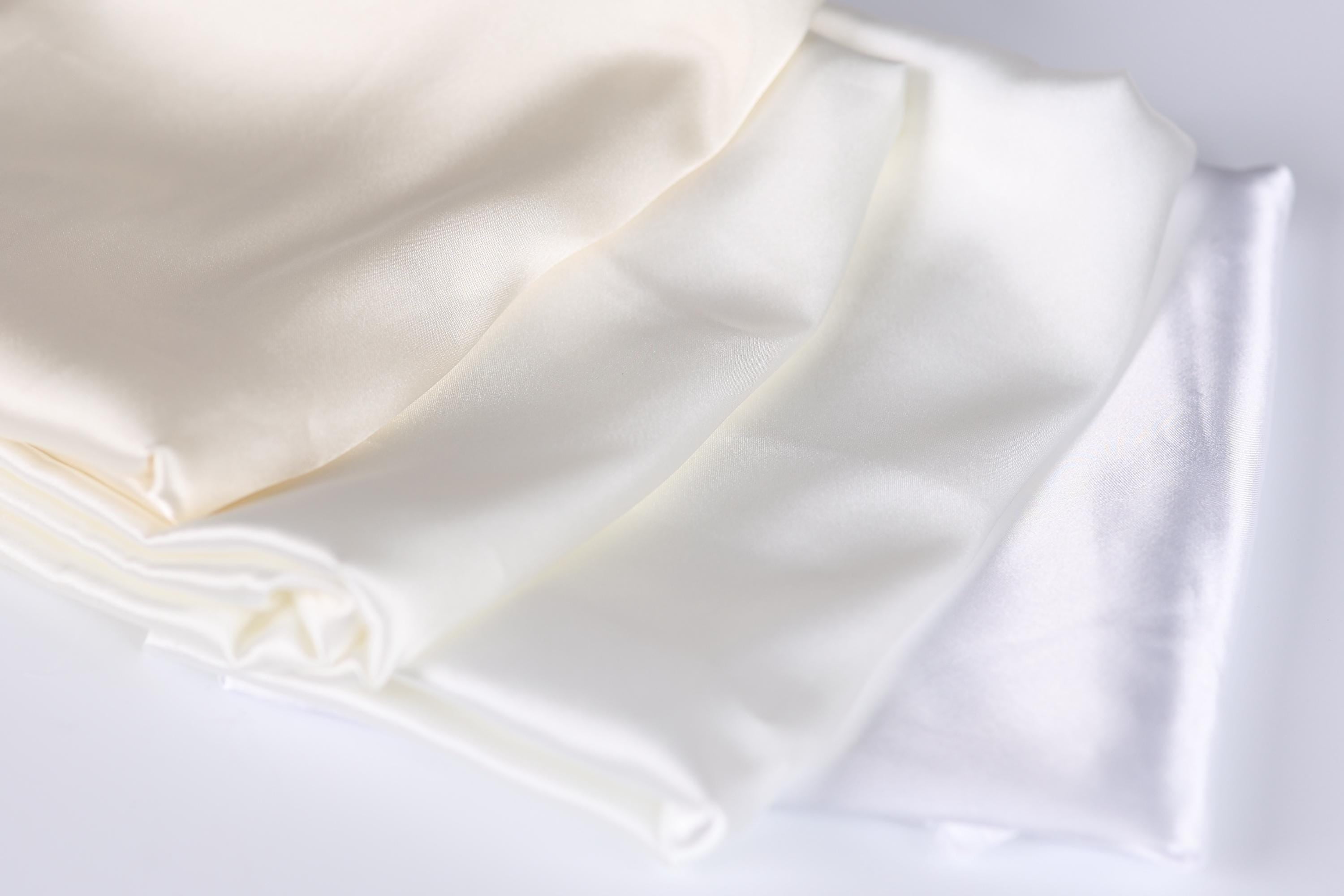 a close-up view of three white fabric pieces, possibly silk or satin, arranged in a horizontal line.